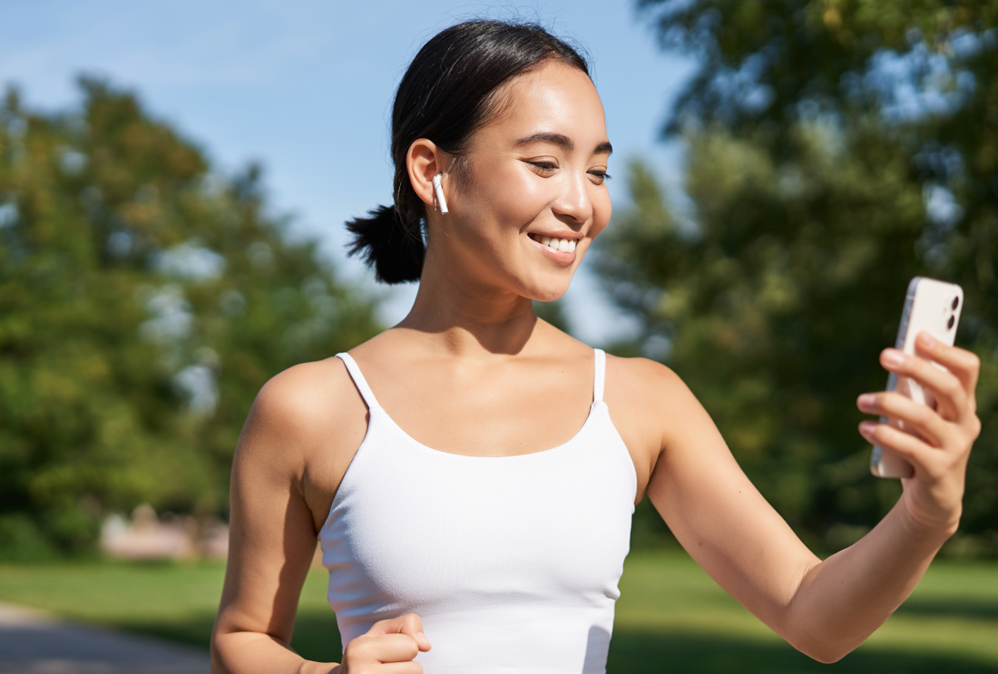 "Happy young woman exercising for weight loss and a healthy lifestyle, holding a smartphone in her hand."